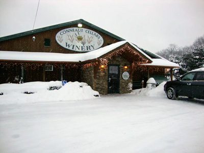 Conneaut Cellar Winery building in Conneaut Lake PA is shown covered in snow as customers enter the gift shop during the holidays.